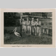 Five men in uniform leaning on fence looking at pelican. Written on front:  Iwao, Myso, Leo, Jun (ddr-ajah-2-10)