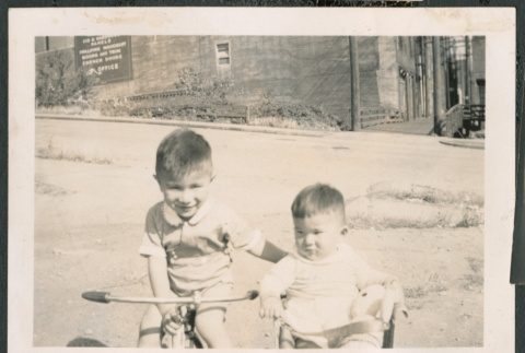 Photo of Paul Ima on a tricycle and Kenji Ima in a wagon (ddr-densho-483-834)