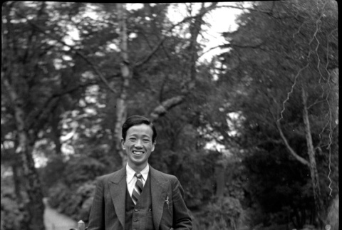 Man in suit standing by metal fence (ddr-densho-426-2177)