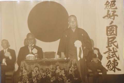 Buddhist priest and others before a Japanese flag (ddr-njpa-4-311)