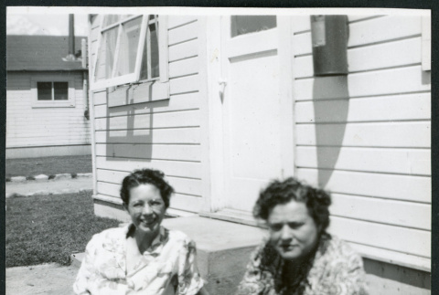 Photograph of Lucy Adams and Dagmar Quarnstrom sitting on the grass in front of staff housing at Manzanar (ddr-csujad-47-171)