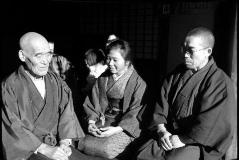 Two men and a woman seated in doorway of house (ddr-densho-426-312)