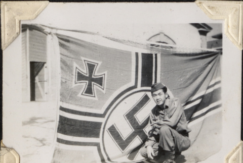 Man kneeling by Nazi flag (ddr-densho-466-736)