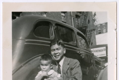 Man and child sitting next to car (ddr-densho-483-638)