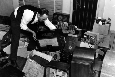 Man stacking confiscated radios (ddr-densho-36-31)