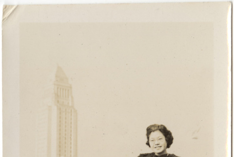 Tomoye (Nozawa) Takahashi standing with large building in background (ddr-densho-426-1779)