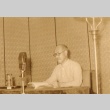 Man seated behind microphone (ddr-njpa-4-240)