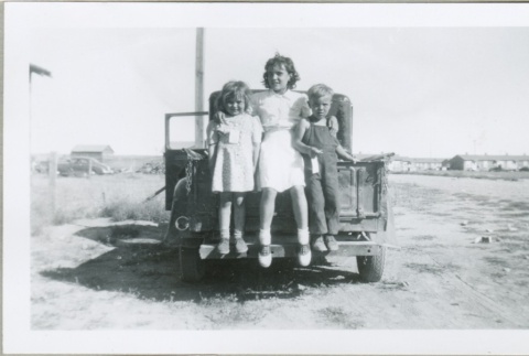 Three children standing on a truck (ddr-densho-300-98)