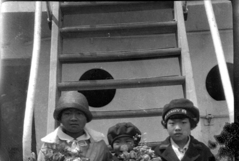Four children sitting on stairs on ship, holding flowers (ddr-densho-426-1715)