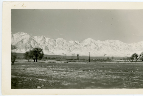 Photograph of Manzanar with snow on the ground and guard tower in the background (ddr-csujad-47-336)