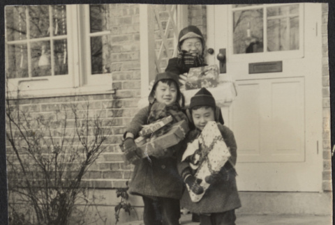 Children holding presents in front of house (ddr-densho-523-169)