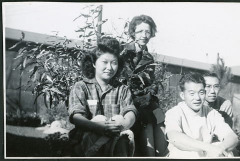 Photograph of four people posing in front of the Manzanar hospital (ddr-csujad-47-257)