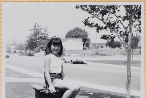 Girl sitting on trash can in yard (ddr-densho-522-103)