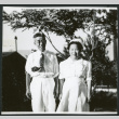 Photograph of a couple standing in front of trees and buildings at Manzanar (ddr-csujad-47-261)
