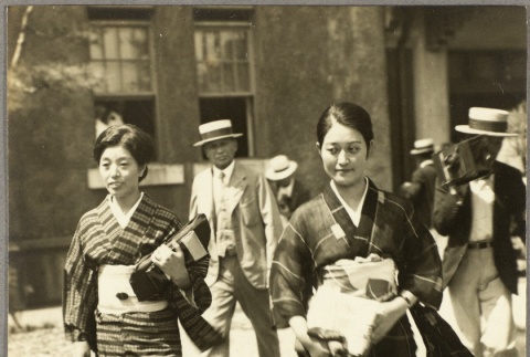 Two women walking carrying bundles of fabric (ddr-njpa-13-1358)