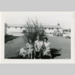 Man and two women sitting in front of camp administration building (ddr-manz-8-10)