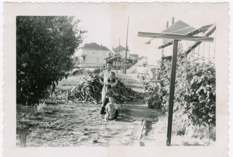 Dale, Irene, John, and Jerry Shigaki in yard with pile of wood (ddr-densho-456-21)