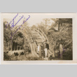 Tomoye (Nozawa) Takahashi standing by Moon bridge in garden (ddr-densho-426-1877)