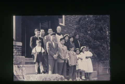 (Slide) - Image of priest with men, women and children on steps outside building (ddr-densho-330-176-master-50bc0e047c)