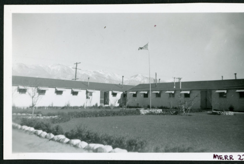 Photograph of the Manzanar administrative buildings with a flag flying (ddr-csujad-47-156)