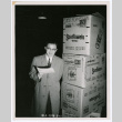 Photo of Ai Chih Tsai in front of Relief Supplies (ddr-densho-446-440)