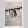 Sally Domoto walking with toddler outside barracks (ddr-densho-329-1334)