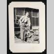 Gary Kikawa leaning on a stack of firewood (ddr-densho-542-730)