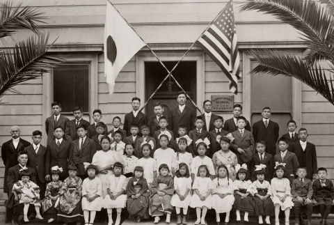 School children and teachers outside school with Japanese and American flags (ddr-ajah-6-607)