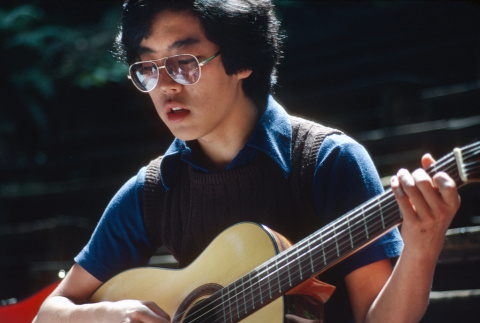 Kyle Kashima playing guitar at morning watch (ddr-densho-336-1320)