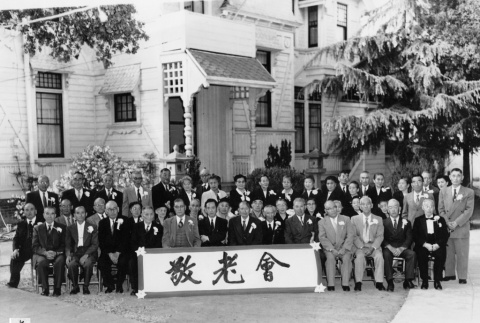 Group photo outside building, holding banner in Japanese (ddr-ajah-3-185)
