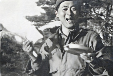 Shiro Robert Yamaguchi standing in snow eating from mess kit. (ddr-densho-474-225)