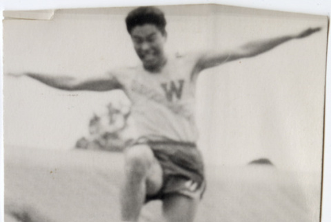 Man in track uniform doing long jump (ddr-densho-426-444)