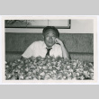 Man poses with pile of fortune cookies (ddr-densho-499-52)