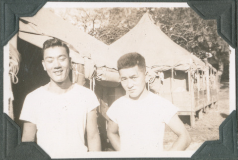 Two men standing outside tents (ddr-ajah-2-576)