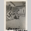 Man kneeling by Nazi flag (ddr-densho-466-344)