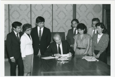 Governor Booth Gardner signing redress a document (ddr-densho-10-17)