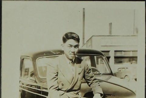 Kozo Minaga sitting on a car (ddr-densho-328-543)