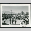Photograph of a large group of incarcerees standing near the entrance of Manzanar (ddr-csujad-47-10)