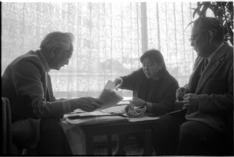 Loni Ding, Barry Saiki and Harry Fukuhara looking through clippings (ddr-densho-1007-1168)