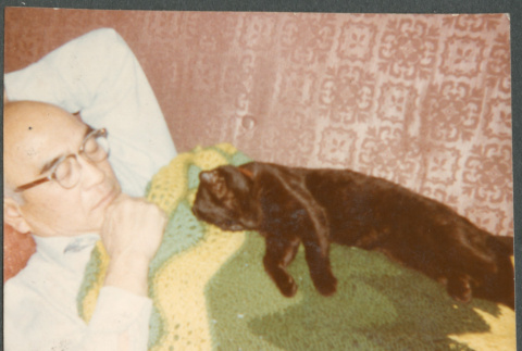 Chester Sakura lying down with cat (ddr-densho-523-643)