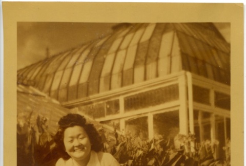 Pee Wee Kusunoki sitting in front of a greenhouse (ddr-manz-6-108)