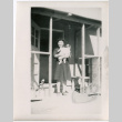 Woman holding baby in doorway of barracks (ddr-densho-329-1327)