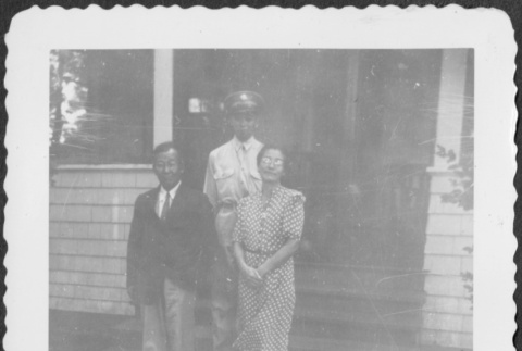 Man in uniform standing on steps of house with man and woman (ddr-densho-434-408)