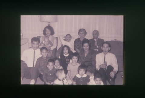(Slide) - Image of men, women and children seated on couch and floor (ddr-densho-330-160-master-3fcaac1e77)