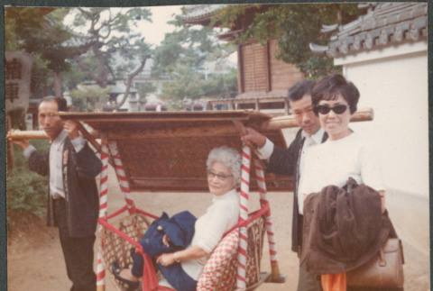 Agnes Sakura being carried by two men with another woman standing (ddr-densho-523-575)