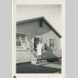 Camp teacher standing outside the back door of a building (ddr-manz-7-107)