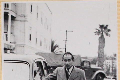 Man standing with hand on car (ddr-densho-522-3)