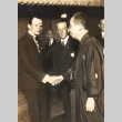 Buddhist priest shaking hands with a man while others look on (ddr-njpa-4-307)