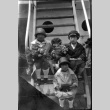 Four children sitting on stairs on ship, holding flowers (ddr-densho-426-1715)