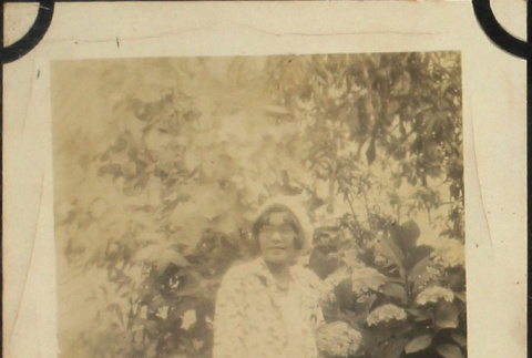 Woman standing by flowers holding tennis racket (ddr-densho-423-499)